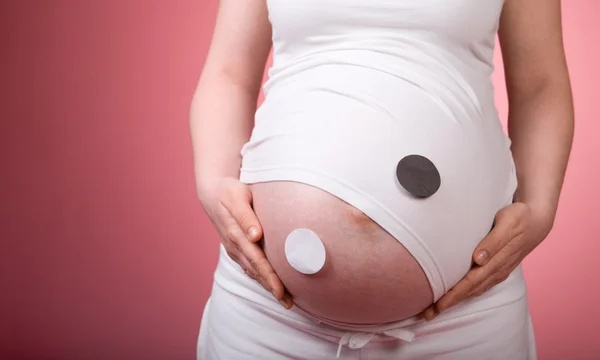週妊娠中の腹に Yin ヤン記号です ピンクの背景にわたって撮影スタジオ — ストック写真
