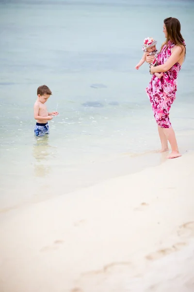 熱帯の白砂のビーチで二人の子供を持つ若い母親 — ストック写真