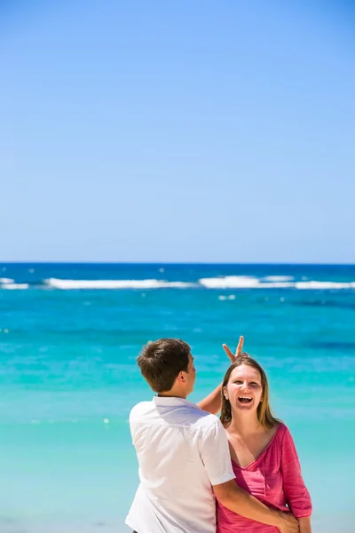 若い幸せなカップルは笑っています 男はカメラに戻ってなっています 背景にターコイズ ブルーの海 — ストック写真