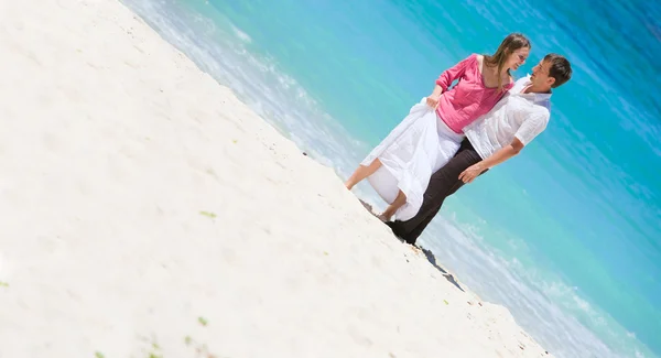 白色的沙滩上年轻快乐的夫妻 — 图库照片