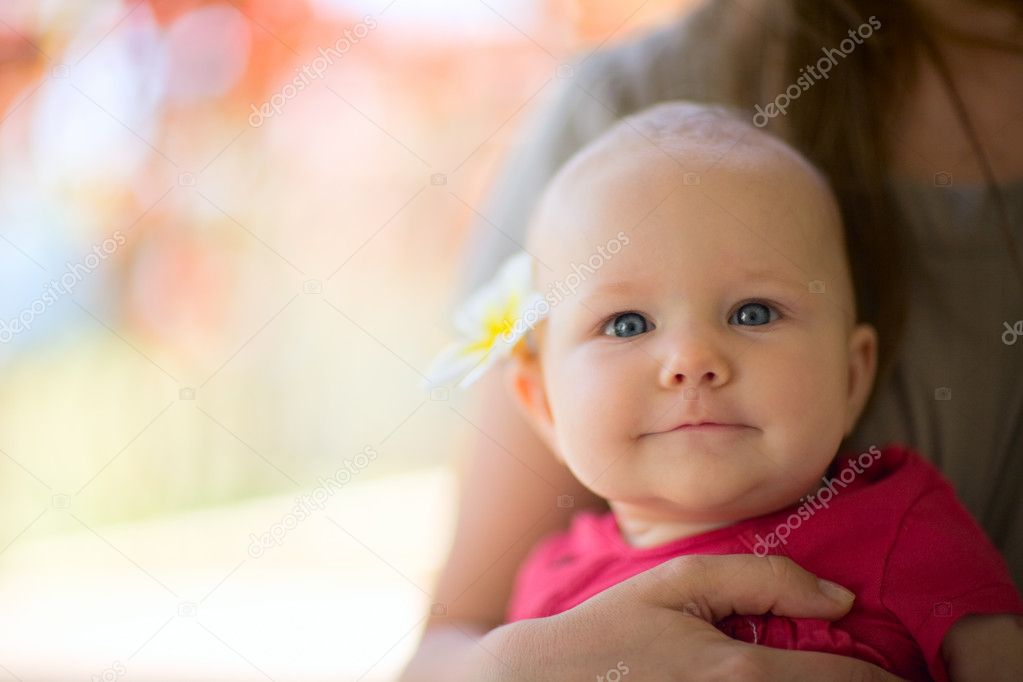 Portrait of cute 5 months old baby girl with tropical flower outdoor