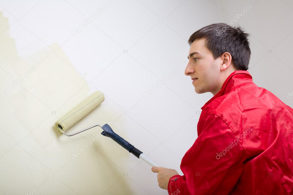 Man painting a wall. Painter in red overall painting wall in light green color