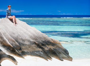 Anse kaynak d'Argent Beach de Seyşeller granit kaya üzerine oturan kadın