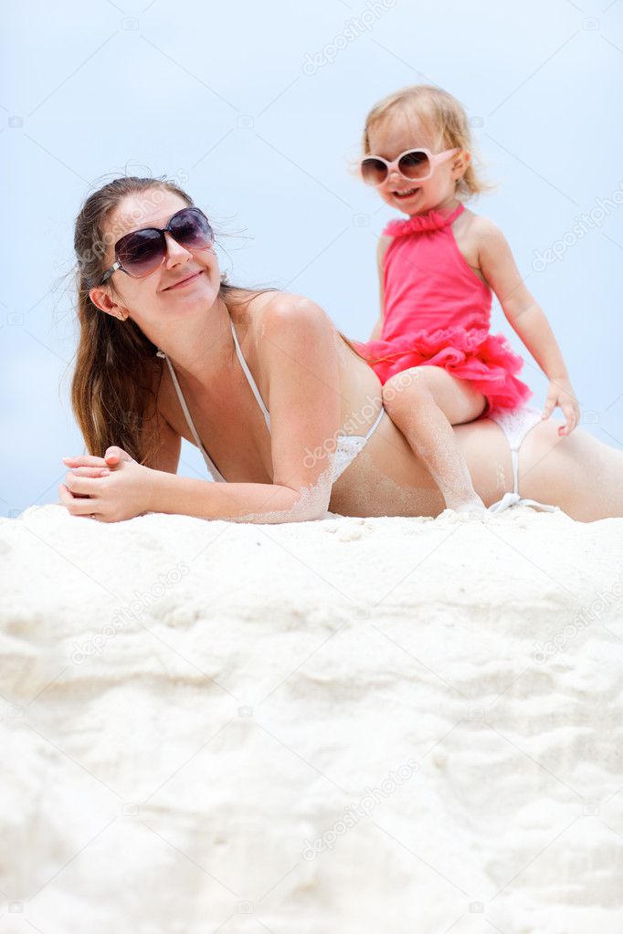 Young mother and her adorable little daughter relaxing at beach