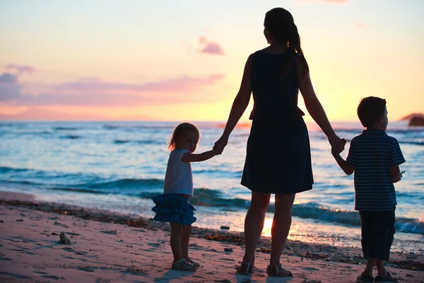 母亲和两个孩子在日落海滩上的剪影 — 图库照片