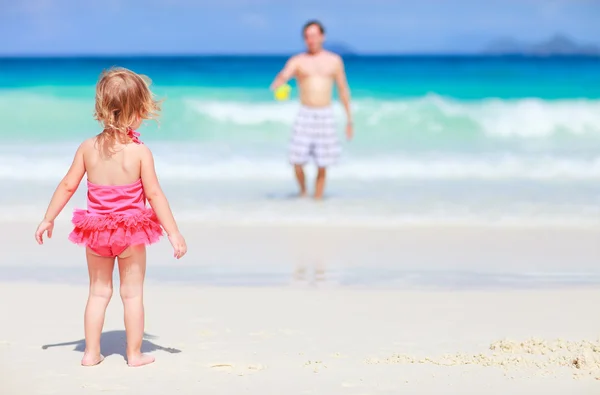 彼女の父親と白い砂のビーチで遊び心のある幼児の女の子の背面します — ストック写真