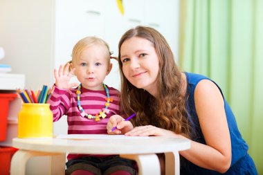 Young mother and her little daughter drawing together clipart