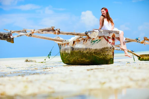 美丽的女孩坐在小船在热带海滩的桑给巴尔岛上 — 图库照片