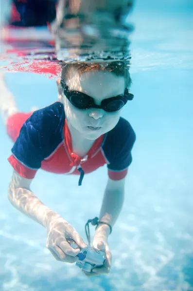 Cute 6 years old boy swimming underwater and making photos