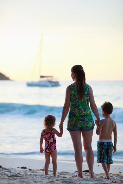 母と二人の子供のシルエット夕暮れ時のビーチに — ストック写真