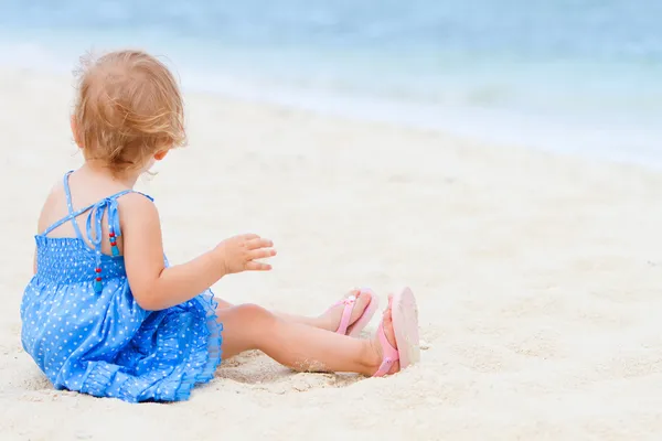 Toddler girl sitting on white sand beach — Stock Photo, Image