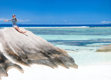 Woman sitting on top of granite rock clipart