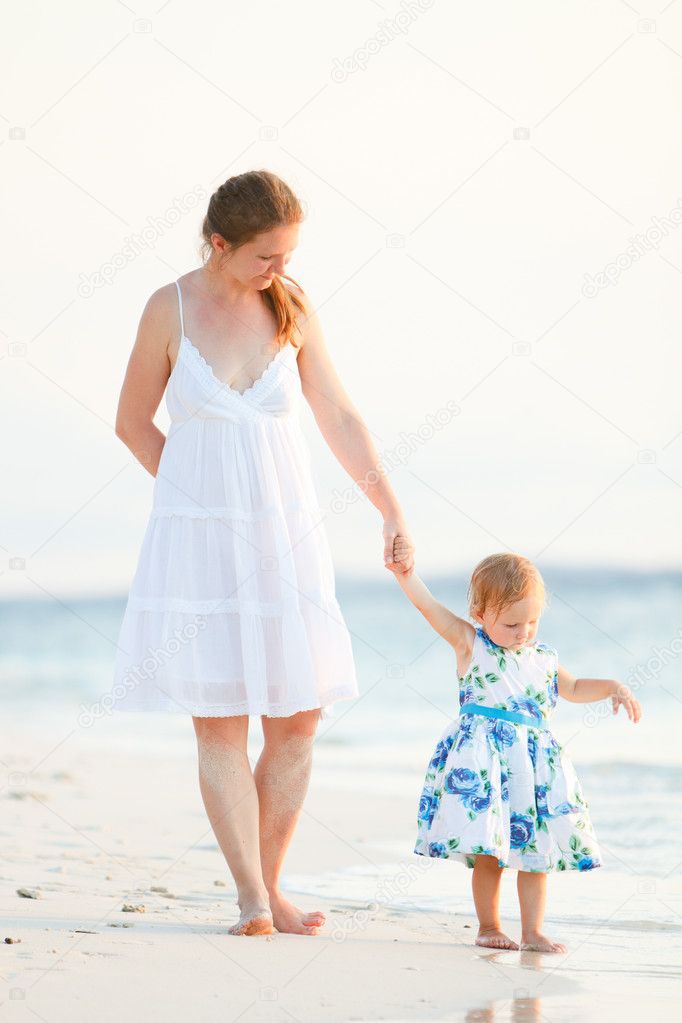 Mother and daughter on tropical beach at sunset