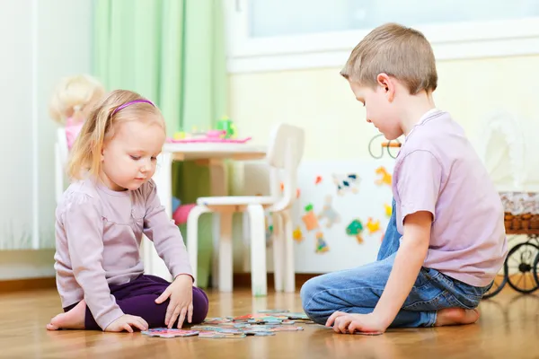 Brother and sister solving puzzle — Stock Photo, Image