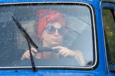 Vintage girl in car under rain clipart