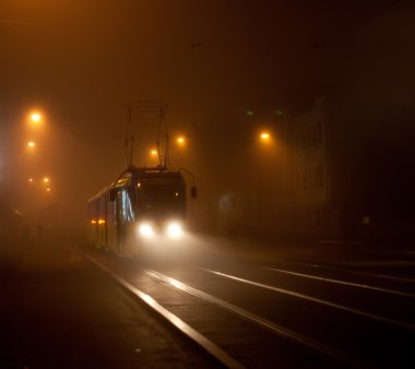 Tram moving on city street in the fog clipart