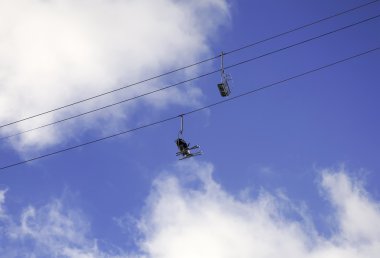 Teleferik gökyüzünde sandalyelere oturan kayakçı çifti