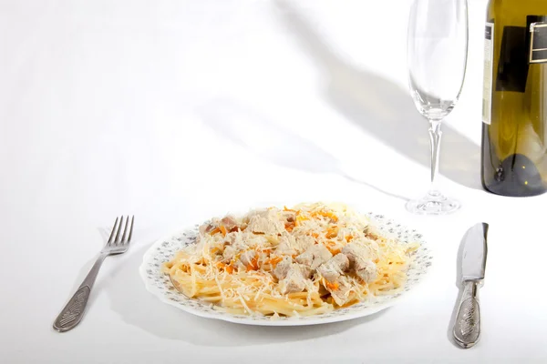 Spaghetti con carne e carota su piatto, bicchiere di vino e bottiglia — Foto Stock