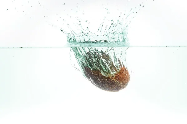 Кокос в водяном брызге с изумрудной тонировкой изолирован на белом — стоковое фото