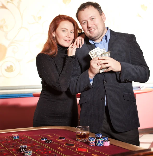 Happy pair with money near roulette table — Stock Photo, Image