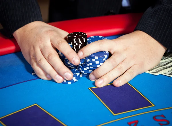 Mão com fichas e notas de $na mesa — Fotografia de Stock
