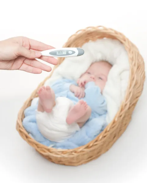 Pasgeboren baby in de mand met temperatuurmeter — Stockfoto