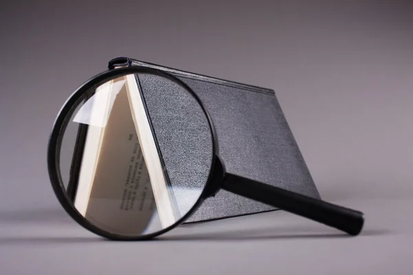 Libro sobre gris a través de lupa — Foto de Stock