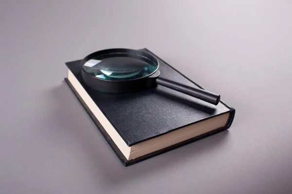 Magnifying glass on closed book — Stock Photo, Image