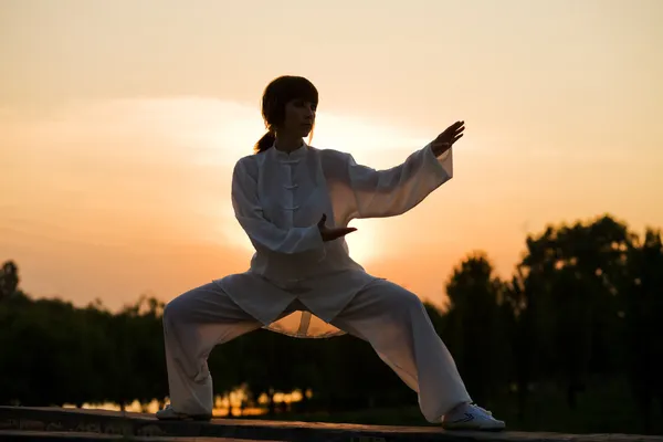 Mujer en traje blanco hace ejercicio taiji chuan —  Fotos de Stock