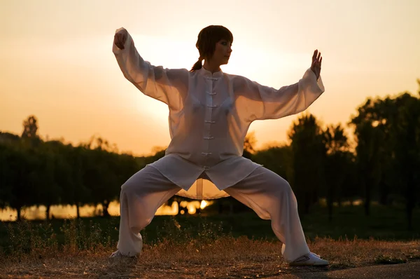 Жінка в білому костюмі робить вправи Тайцзі Чуань — стокове фото