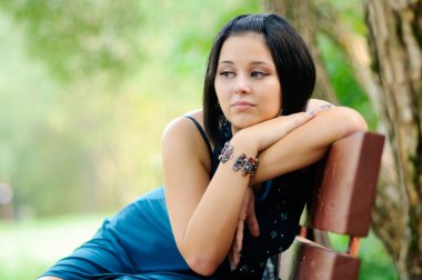 Pretty girl siiting on a bench in a park clipart