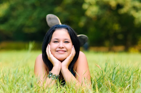Красивая девушка расслабляется на открытом воздухе на зеленой траве — стоковое фото