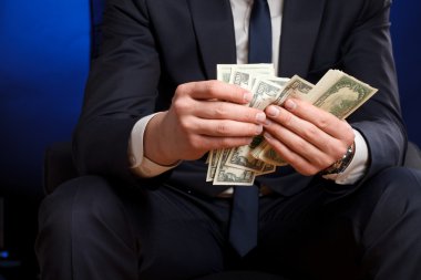 Businessman counts money in hands. clipart