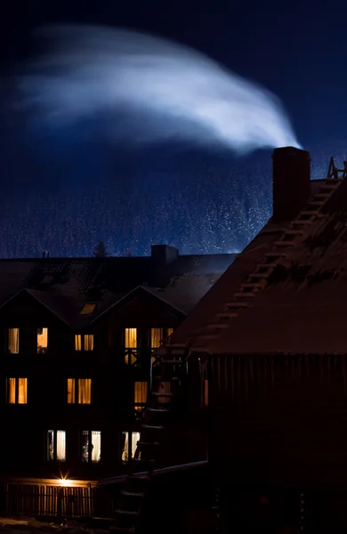 stock image Beautiful view with smoke on the cottage roof in the winter mountain