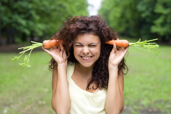 搞笑女孩用胡萝卜在耳朵 免版税图库照片