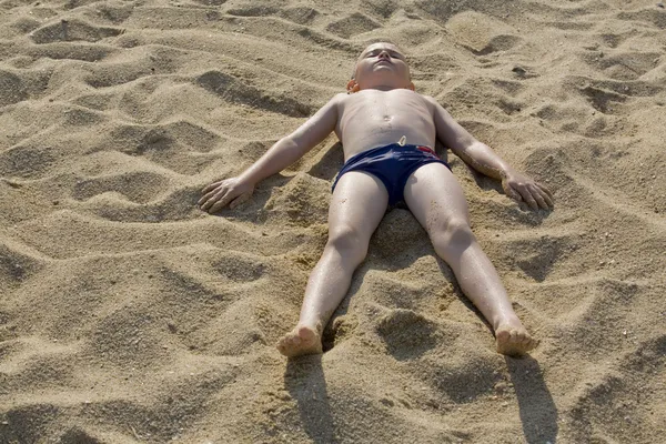 Хлопчик лежить на піску — стокове фото