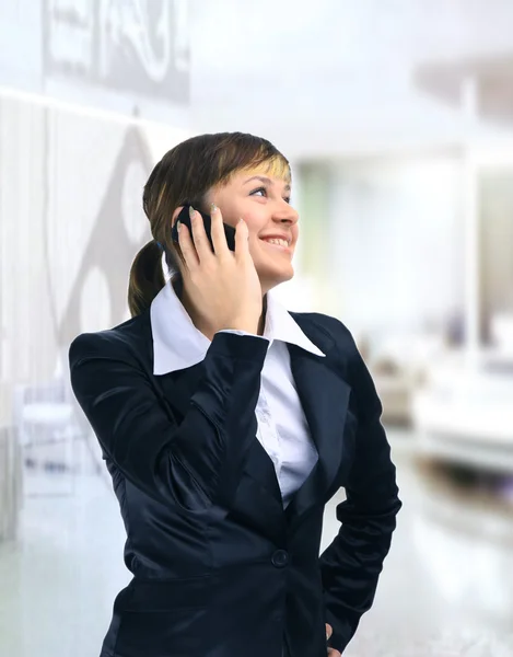 近代的なオフィスビルで電話で笑顔の美しいビジネス女性 — ストック写真