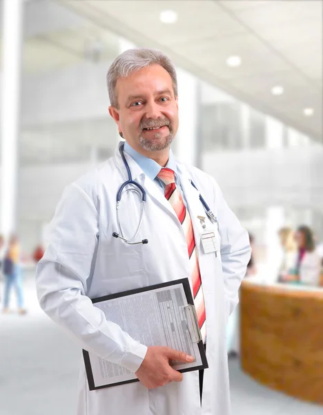 Felice sorridente medico maturo che scrive sugli appunti in un ospedale moderno — Foto Stock