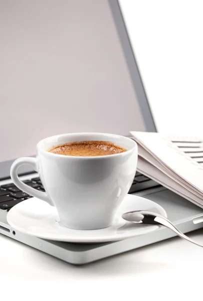 Φλιτζάνι ζεστό cappuccino σε φορητό υπολογιστή και εφημερίδα — Φωτογραφία Αρχείου