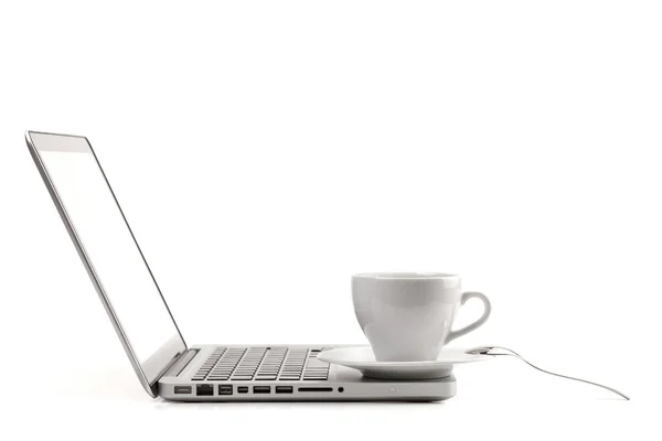 Чашка капучино з ложкою на ноутбуці — стокове фото