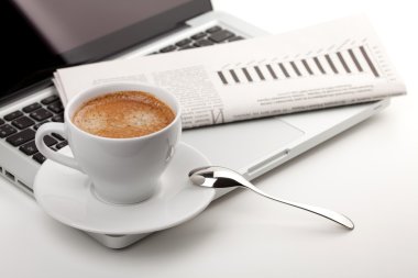 Laptoplu ve gazeteli cappuccino bardağı