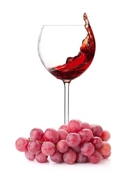 Stříkající červené víno ve sklenici a hrozny — Stock fotografie