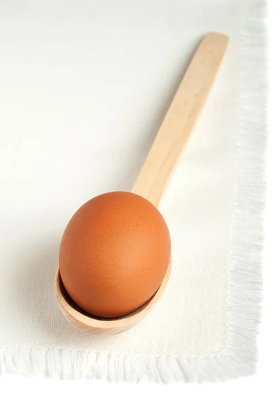 stock image Brown egg in a wooden spoon on a white napkin