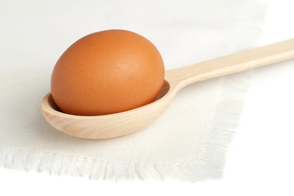 एक सफेद नैपिंग पर एक लकड़ी के चम्मच में ब्राउन अंडे — स्टॉक फ़ोटो, इमेज