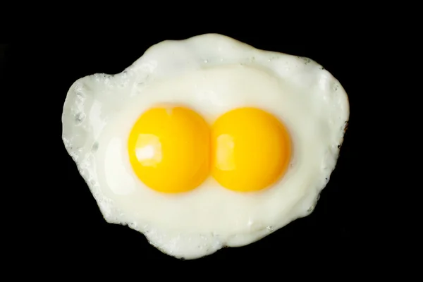 Жареное яйцо из двух желтков на черном фоне — стоковое фото