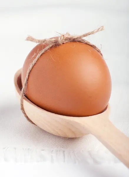 Яйцо в деревянной ложке на белой салфетке — стоковое фото