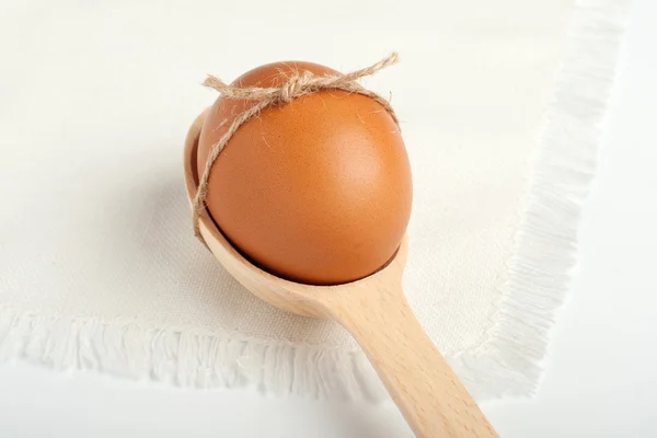Яйцо в деревянной ложке на белой салфетке — стоковое фото