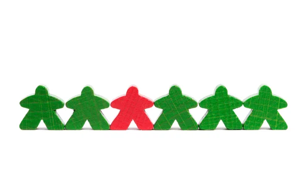 stock image Red wooden figure among green ones symbolizing difference