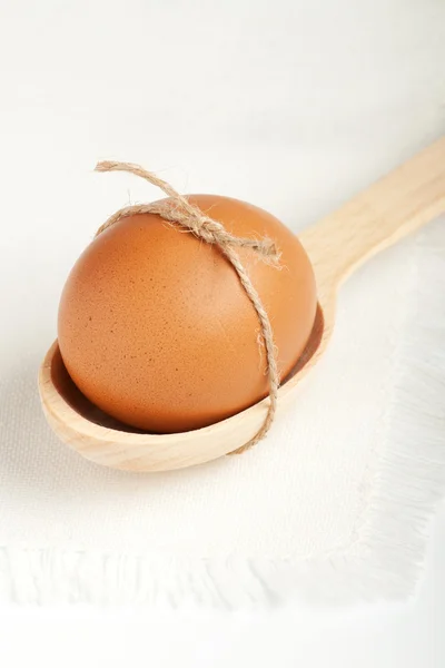 Egg in a wooden spoon on a white napkin — Stock Photo, Image