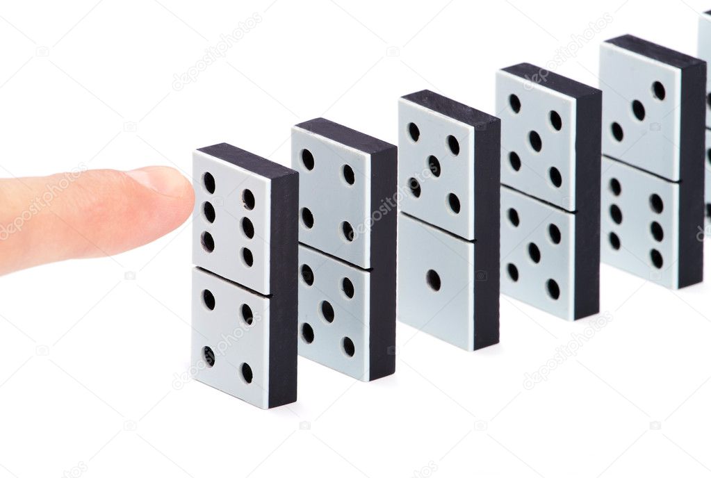 Finger ready to push domino pieces to cause chain reaction